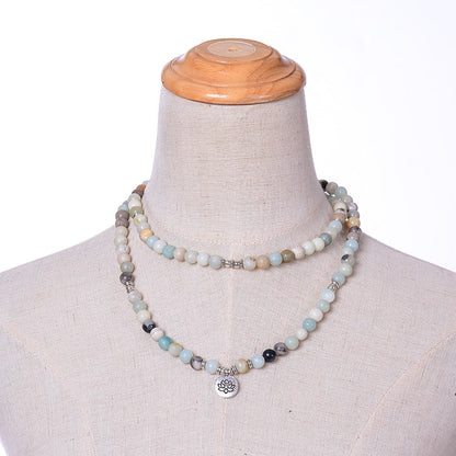 Lotus necklace and bracelet with 108 mala beads of amazonite around the neck of a mannequin.